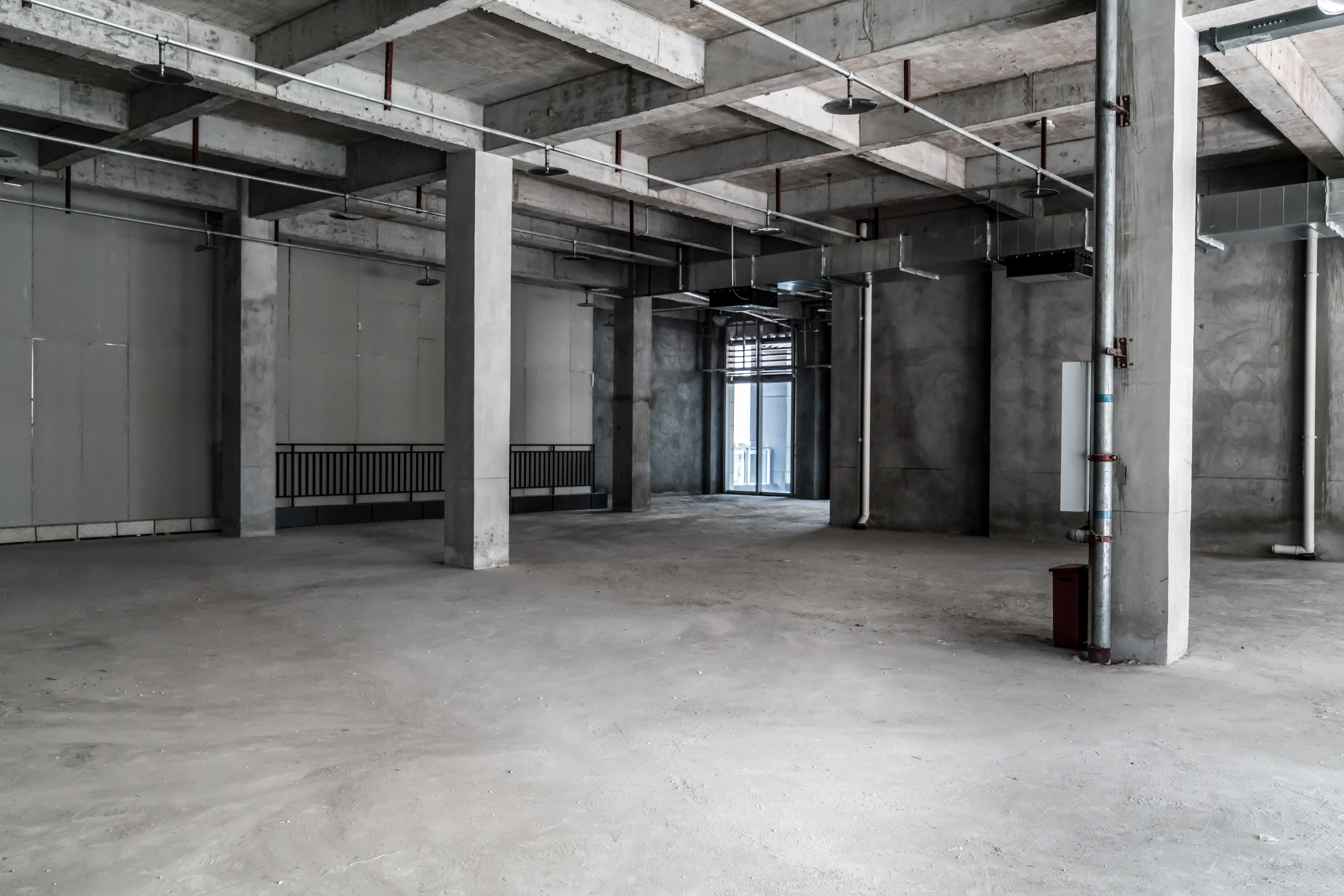 Empty commercial space with exposed concrete and industrial ceiling showing tenant improvement potential